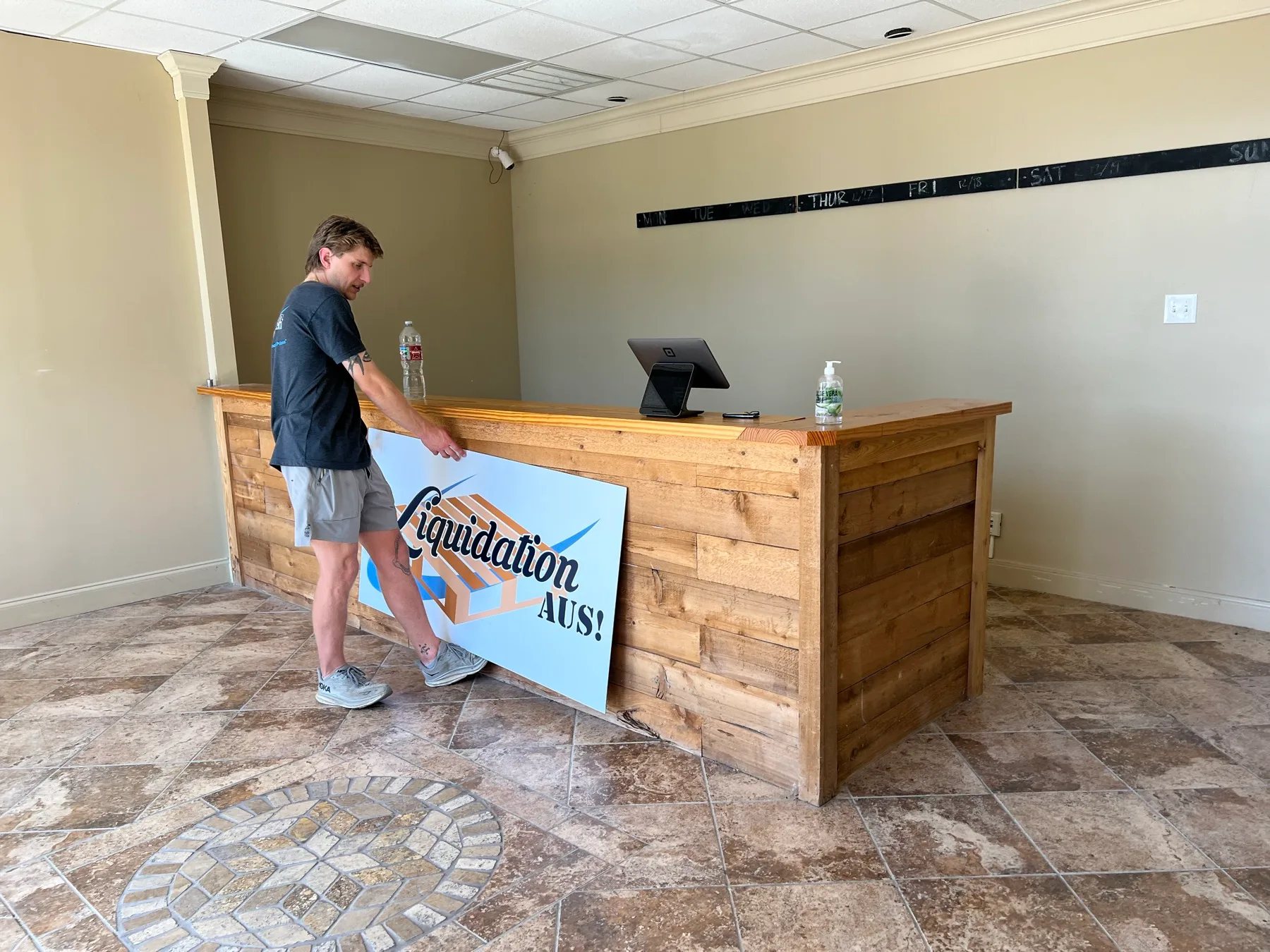 Colton Stephens installing a Liquidation Aus sign at a resale location